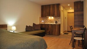 A compact hotel room with a bed, a small kitchenette, a dining area, and a bathroom. - New Gudauri Block 4 - Ski4Life (Kazbegi)