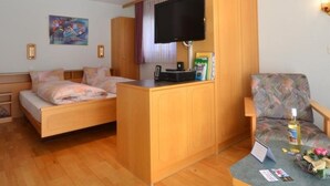 Ein gemütliches Zimmer mit Bett, Schreibtisch, Fernseher und Stuhl.