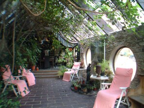 Un patio cubierto con suelo de ladrillo, arcos de piedra y macetas con plantas.