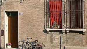 A two-story building with a brick facade, multiple windows with shutters, and a bicycle parked outside. - Ada Bed and Breakfast (Ferrara)