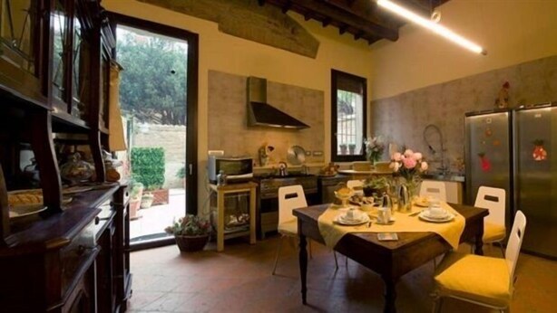 A cozy kitchen with a dining table set for four, a built-in oven, and a refrigerator. - Ada Bed and Breakfast (Ferrara)