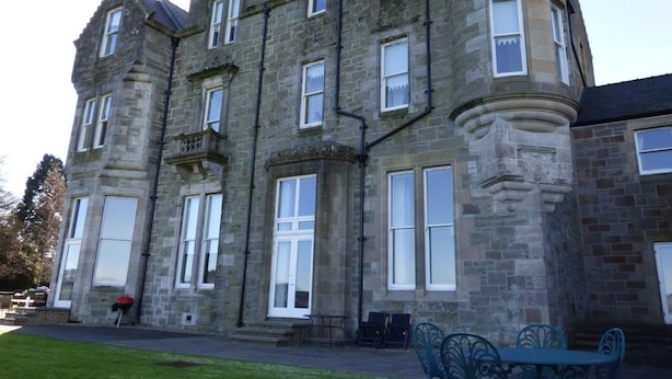 A large stone building with multiple windows and a turret.