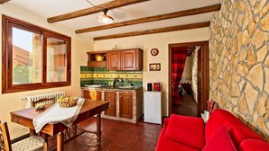 Une cuisine chaleureuse avec des meubles en bois, une table à manger avec des chaises, un canapé rouge et un mur en pierre.