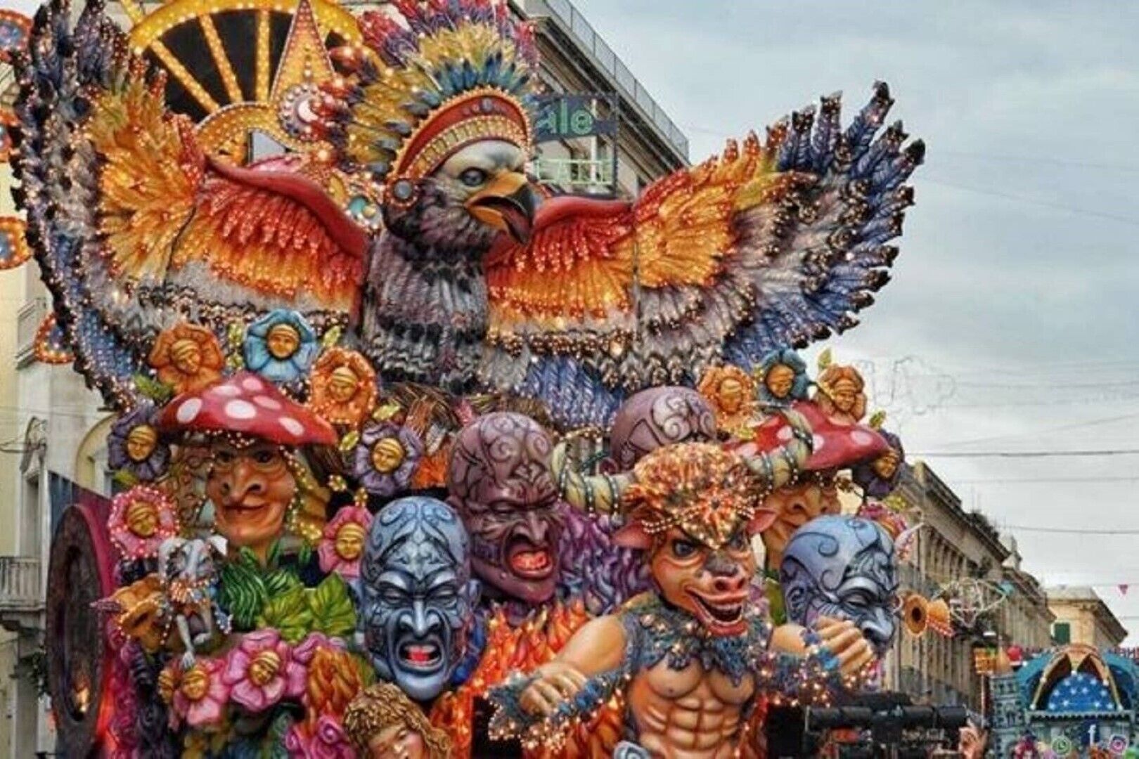 A colorful parade float with various masks and a large bird figure.