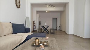 A modern living room with a sofa, coffee table, and a dining area in the background. - Papillon (Astypalaia)