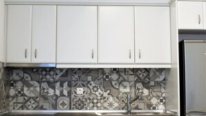A kitchen with white cabinets, a stainless steel oven, a sink, and a refrigerator. - Papillon (Astypalaia)