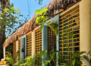 A traditional thatched-roof building with wooden lattice windows and lush tropical plants around it. - Casa da Gloria (Porto Seguro)