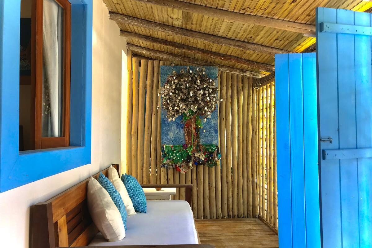 A room with a bed, a wooden bench, and a wall with a decorative tree.