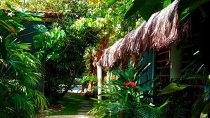 A tropical garden pathway leading to a thatched-roof structure with lush greenery and a clear view of the surrounding area. - Casa da Gloria (Porto Seguro)