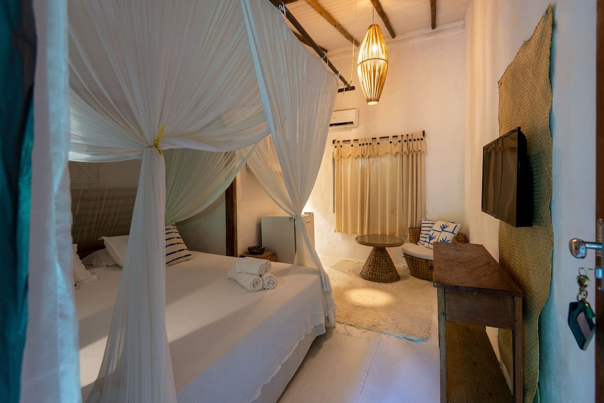 A bedroom with a canopy bed, bedside table, and a small round table with chairs.