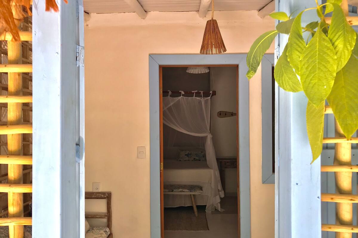 A bedroom with a bed under a canopy, a bedside table, and a power outlet on the wall.