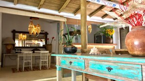 A rustic dining area with a wooden table, chairs, and a large vase of sunflowers. - Casa da Gloria (Porto Seguro)
