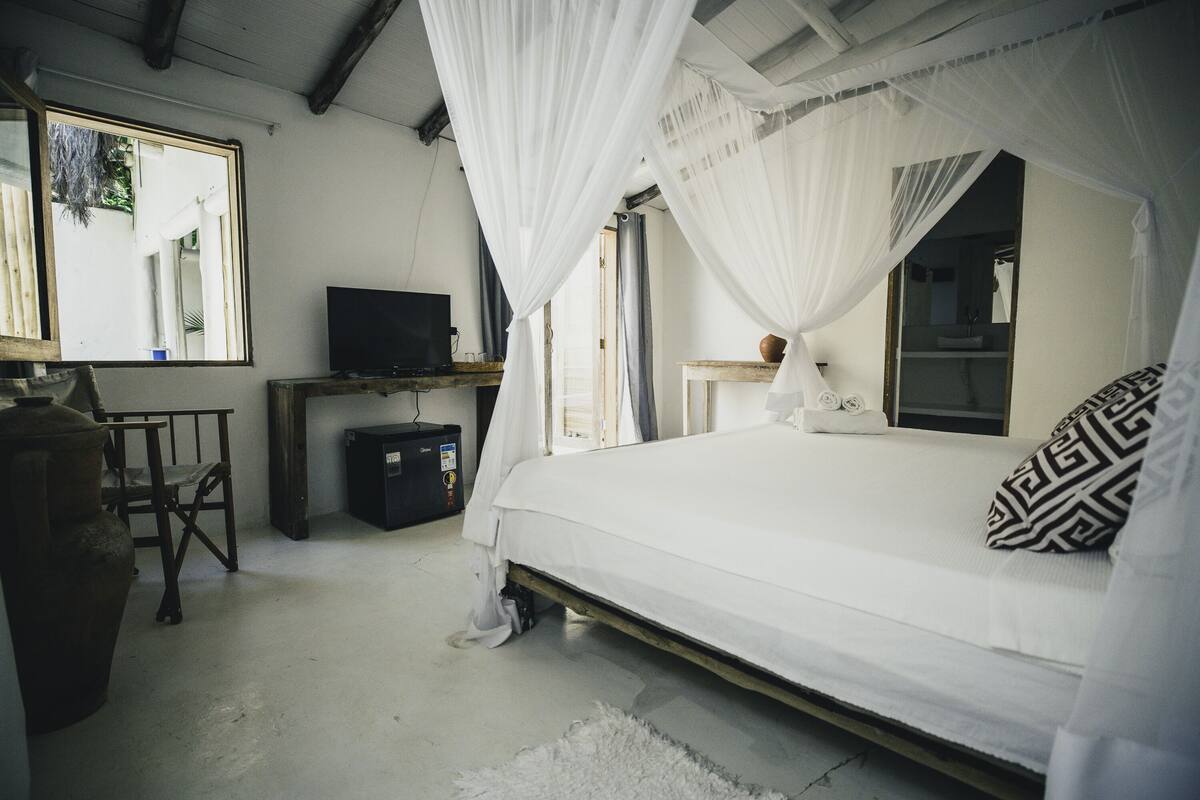 A bedroom with a bed, a television, a desk, and a chair.