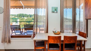 Un comedor con una mesa y sillas, vistas a un balcón con barandilla y una planta en maceta en la pared.