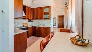 Una cocina moderna con armarios de madera, una isla grande y una zona de comedor con mesa y sillas.