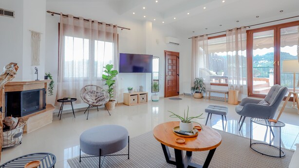 Un salón espacioso con chimenea, asientos cómodos, un televisor de pantalla plana y ventanas grandes que ofrecen vistas al exterior.