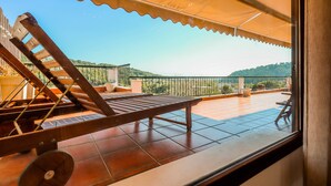 Un balcón con una silla y una mesa de madera, y vista al paisaje, con barandilla.