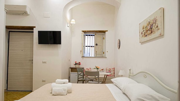 A bedroom with a bed, a desk, a chair, a TV, and a painting. - B&B Al Portone (Pagani)