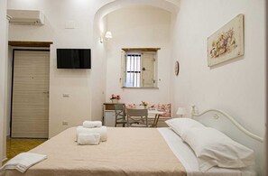 A bedroom with a bed, a desk, a chair, a TV, and a painting. - B&B Al Portone (Pagani)