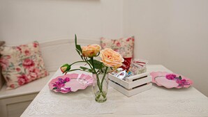 A table with a vase of flowers, a lace tablecloth, and a white crate with items. - B&B Al Portone (Pagani)