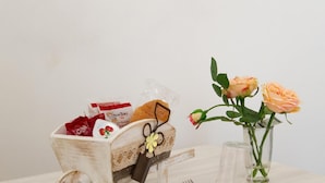 A small wooden cart with a lace doily, a chocolate bar, and a red package on a table. - B&B Al Portone (Pagani)