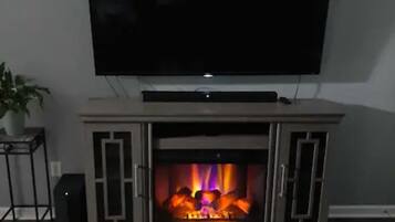 A living room with a flat-screen TV mounted above a fireplace.