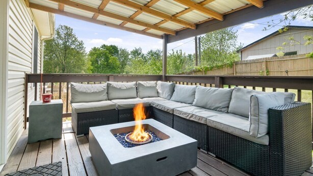 A covered patio with a fire pit, outdoor seating, and a view of the backyard.