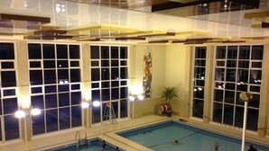 An indoor swimming pool with multiple lanes, large windows, and a ladder. - Residence la Fraisiere (Brussels)
