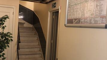 Eine Treppe mit Handlauf, eine Tür mit Notausgangsschild und eine an der Wand befestigte Karte.