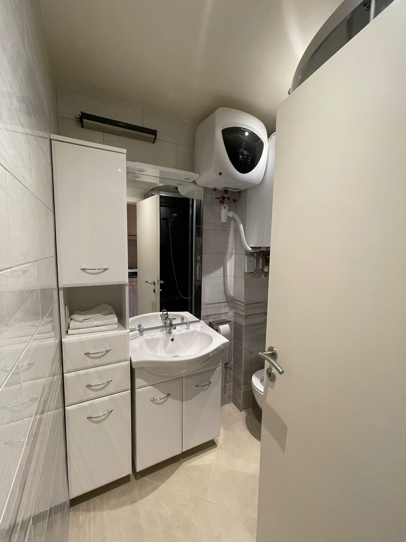 A modern bathroom with a white sink, vanity, and a shower enclosure.