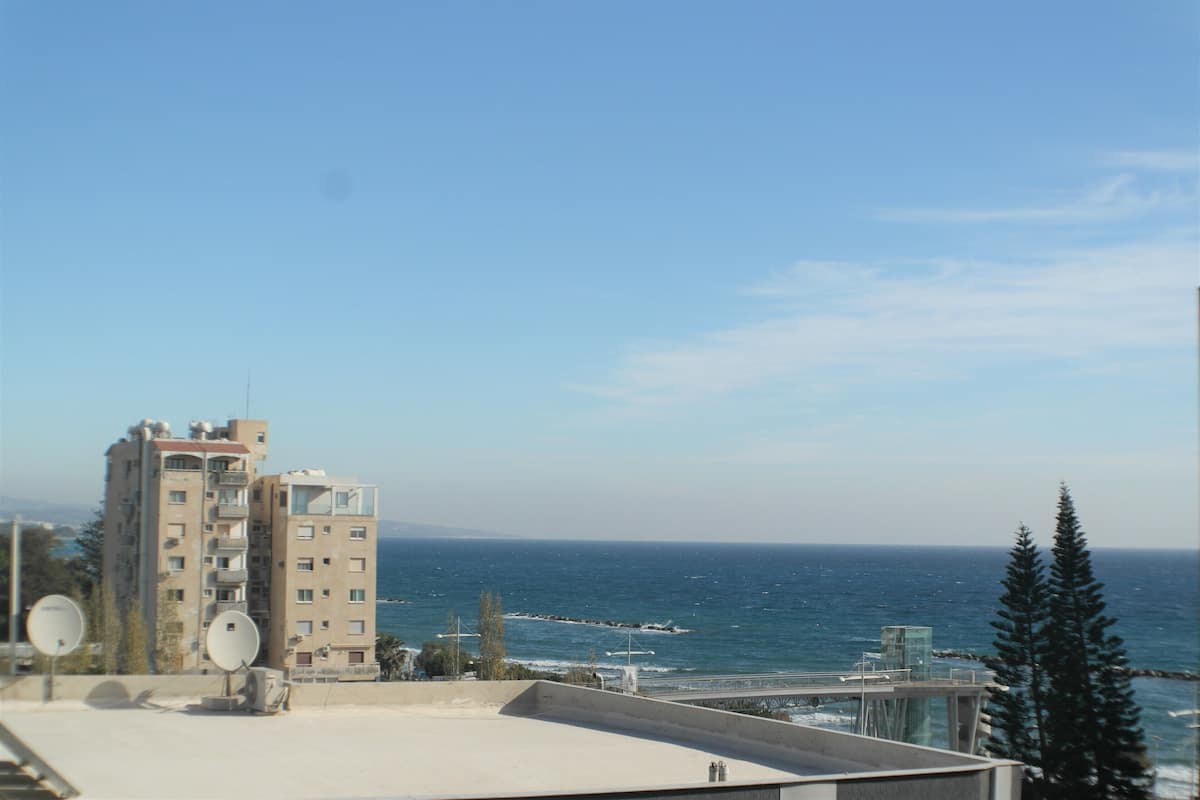 A high-rise building with multiple balconies overlooking a coastal area.
