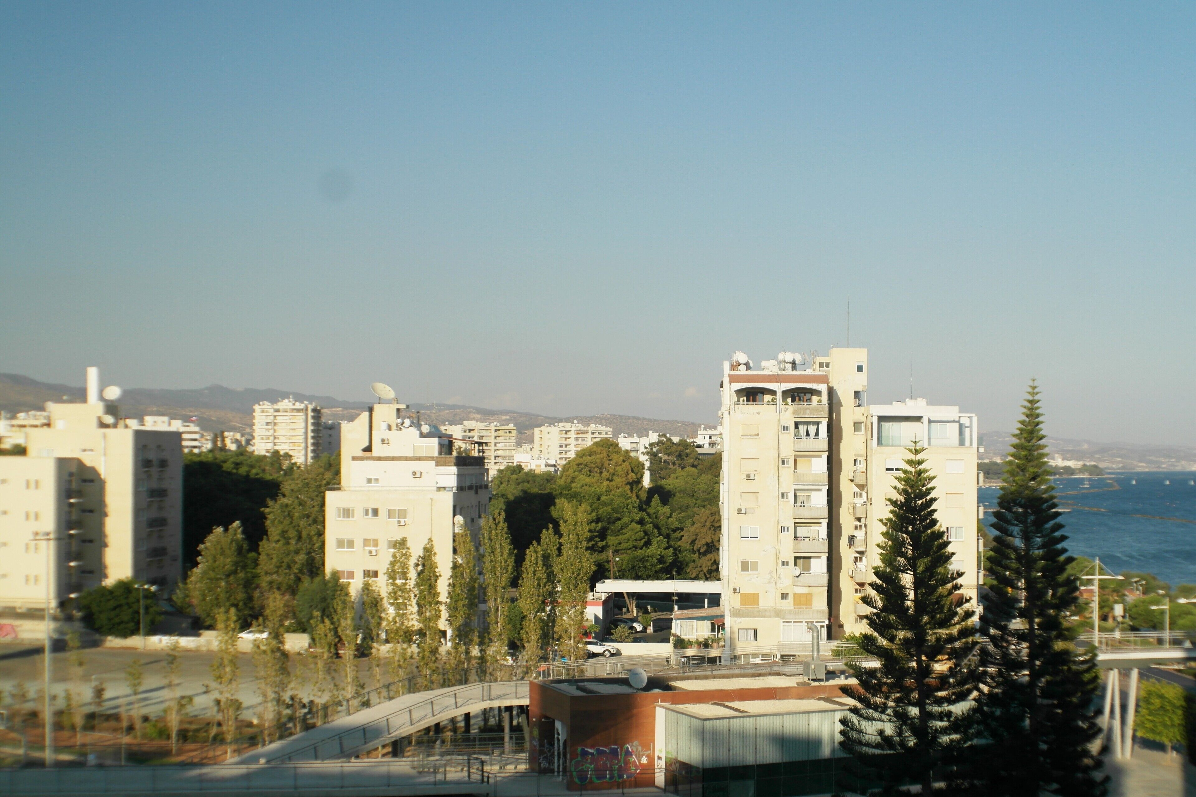 A cityscape with modern buildings, a bridge, and a body of water in the background.