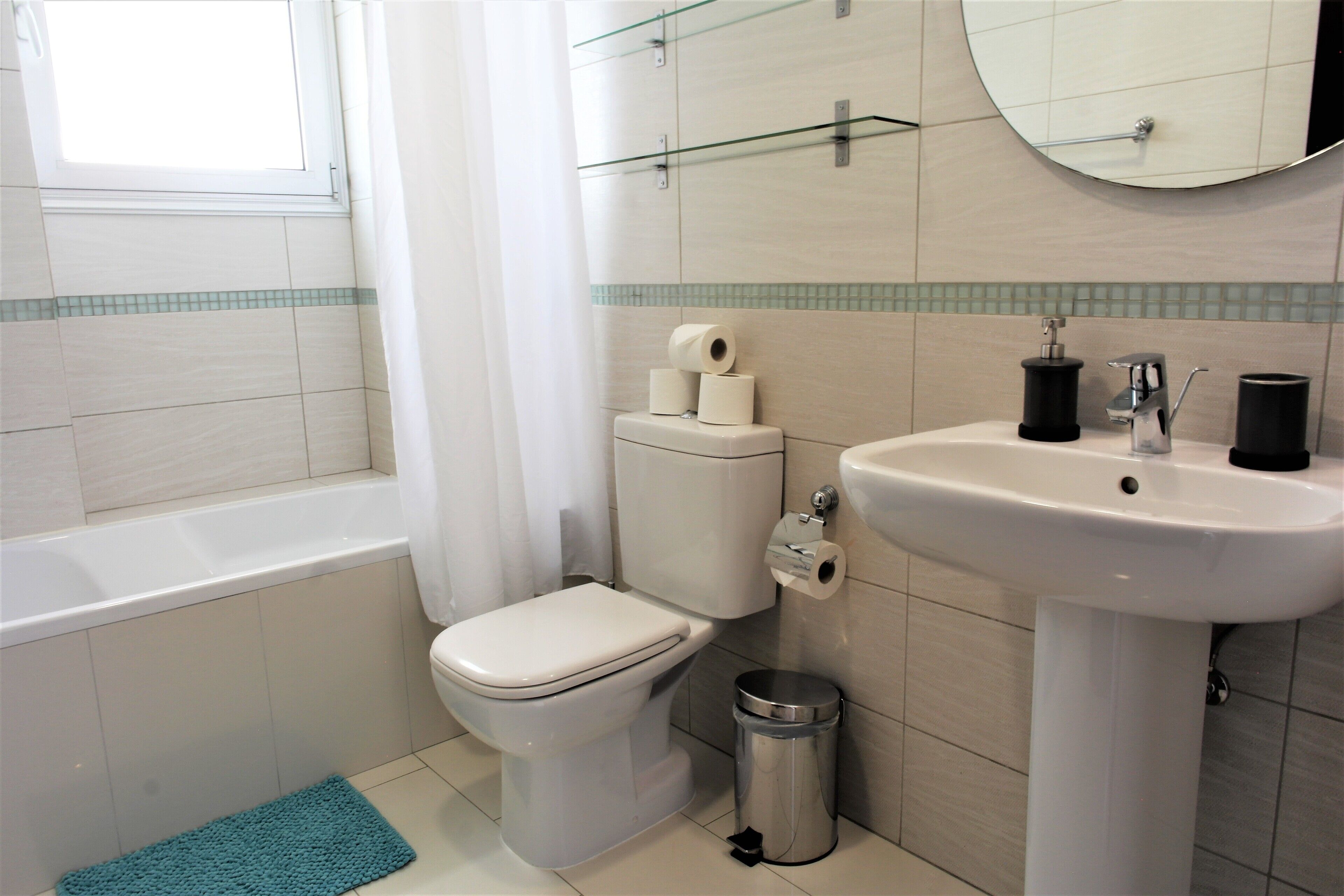 A bathroom with a toilet, sink, and trash can.