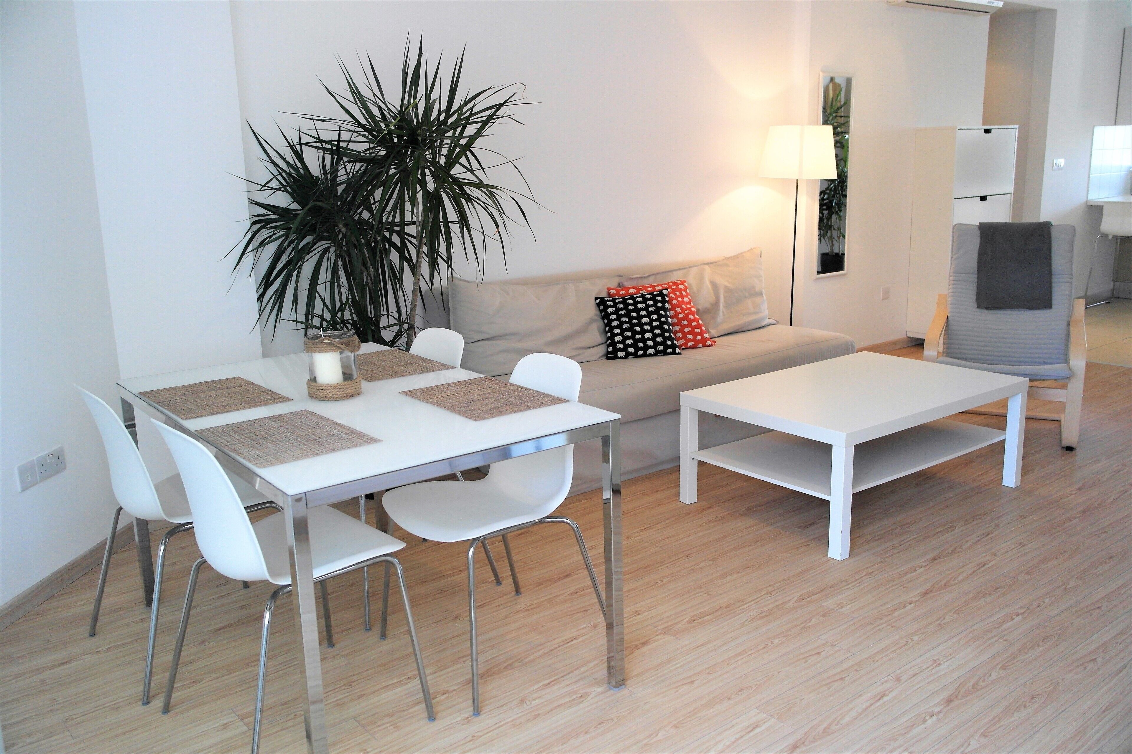 Uma sala de estar moderna com área de jantar, apresentando um sofá, uma mesa de centro e uma mesa de jantar com cadeiras.