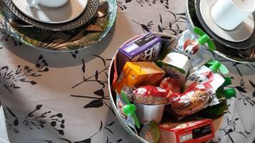 Una mesa con mantel floreado, dos platos con tazas y un bol de aperitivos variados.
