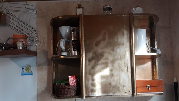A kitchen with a built-in refrigerator and microwave. There is a basket with a plant, a coffee maker, and a coffee container on the shelves. - B&B Chambre Chante Cristal (Target)