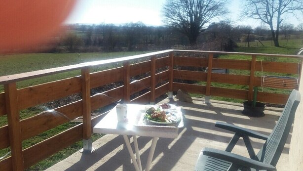 Une terrasse en bois avec une table et des chaises, un banc et un pot de fleurs.