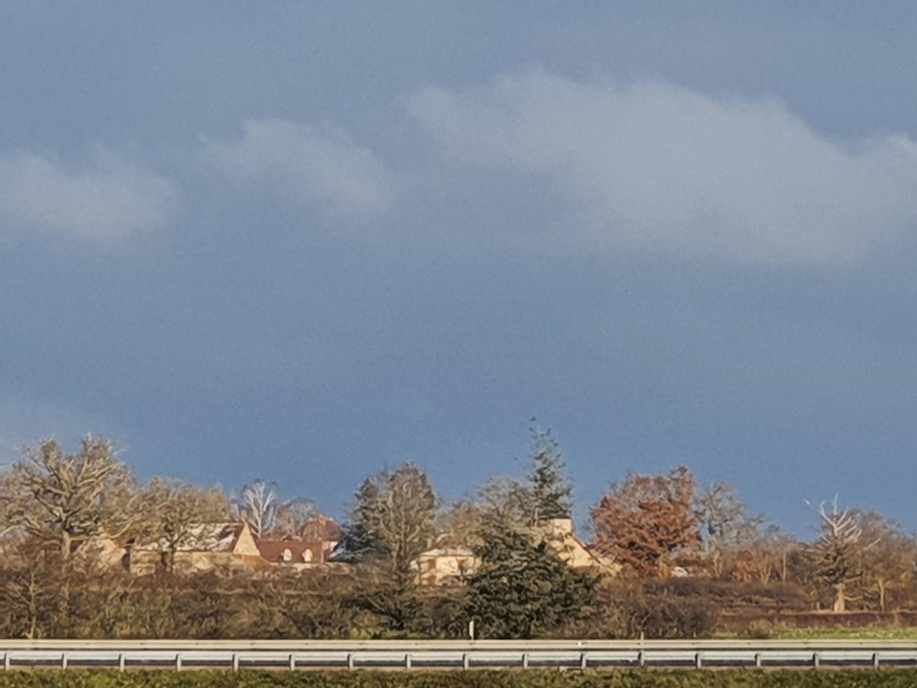 A view of a road with a guardrail and trees in the foreground.