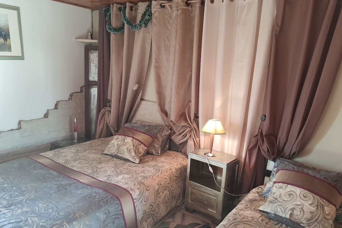 A bedroom with two beds, a nightstand, and a lamp.