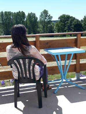 Una persona sentada en una silla junto a una cerca de madera, con una mesa azul a su lado.