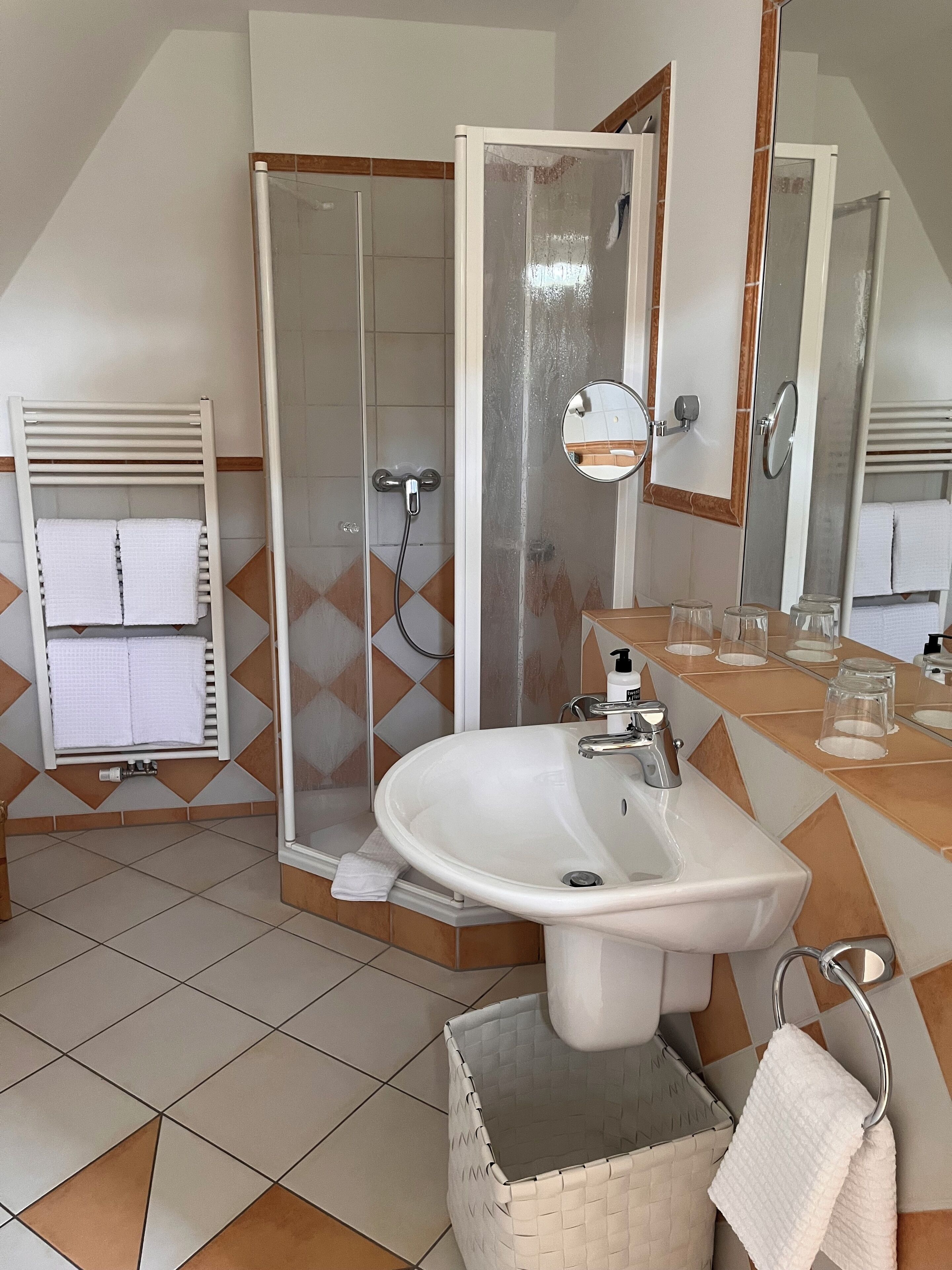 A bathroom with a shower, sink, and towel rack.