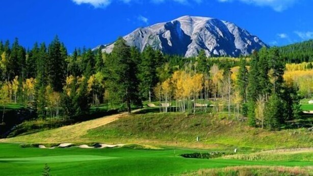 Un campo de golf con una montaña al fondo.