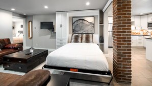Ein modernes Schlafzimmer mit Bett, Couchtisch, Sofa und Fernseher.