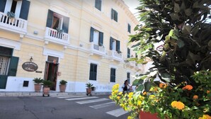 Um edifício amarelo com varandas e plantas em vasos.