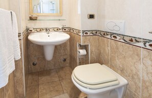 A bathroom with a sink, toilet, and a mirror.