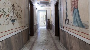 Um corredor com piso de mármore, painéis de madeira e pinturas decorativas nas paredes.