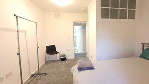 Une chambre à coucher avec un lit, une fenêtre, une chaise et un radiateur.