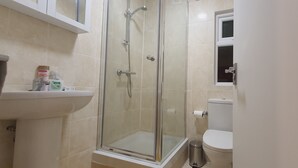 Une salle de bain avec une douche à parois de verre, un lavabo et des toilettes.