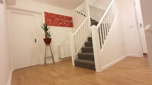 Un escalier avec une rampe blanche, une plante en pot et un tableau abstrait rouge accroché au mur.