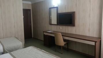 A hotel room with two beds, a desk, a chair, a television, and a wardrobe.